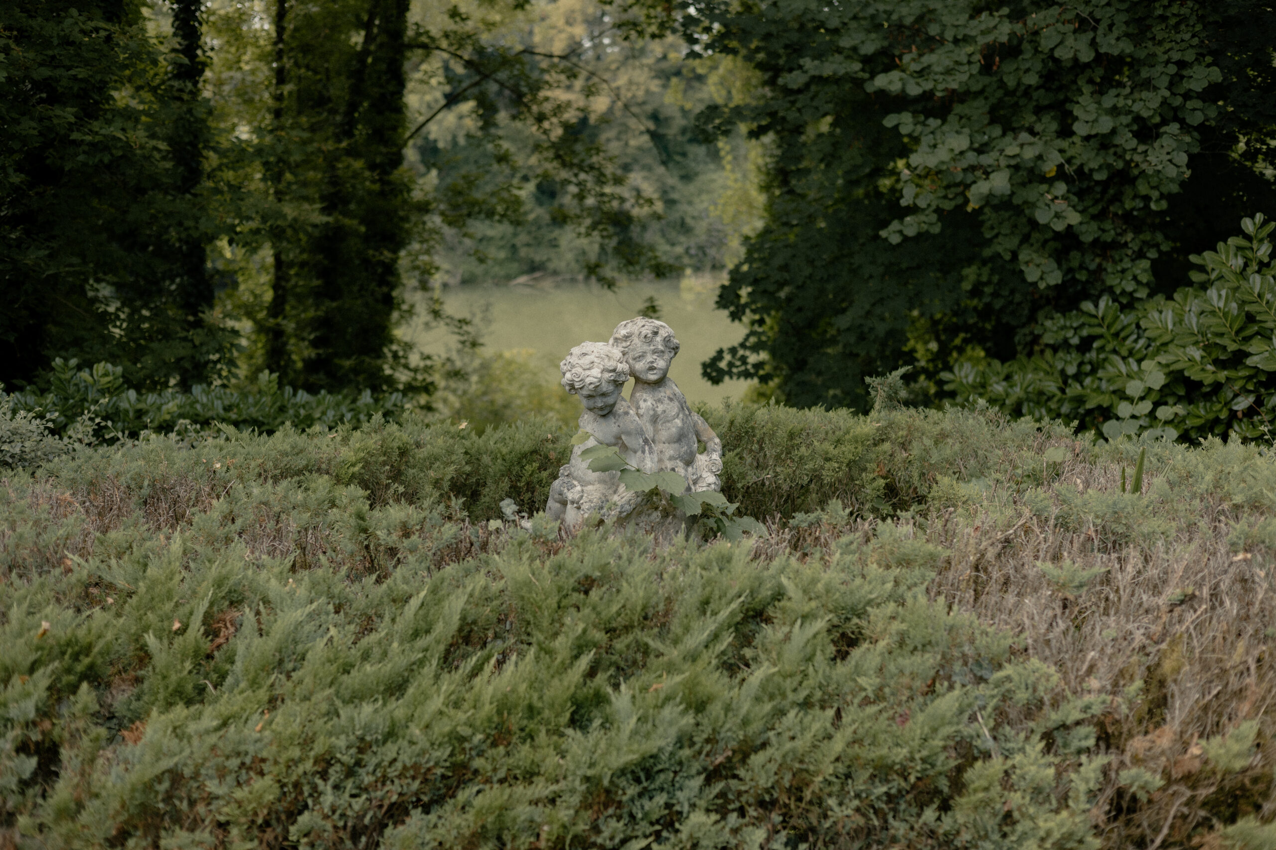 Statue de 2 angelots au milieu de la verdure